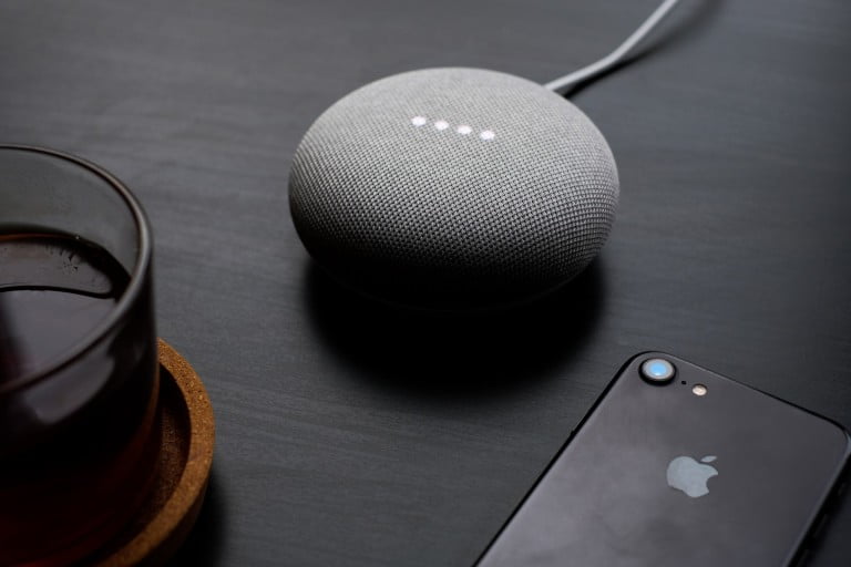 google home mini on a table with iPhone 7