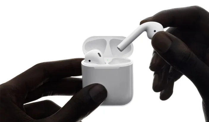 Wirelessly charged Apple AirPods in hands of a person