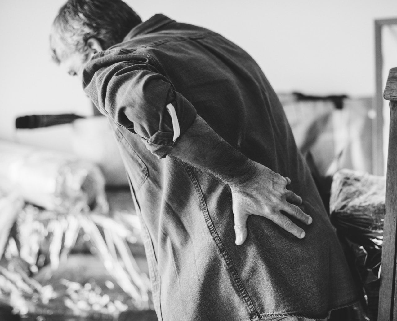 A Black And White Image Of A Man Leaning Forward Because Of Pain In The Back