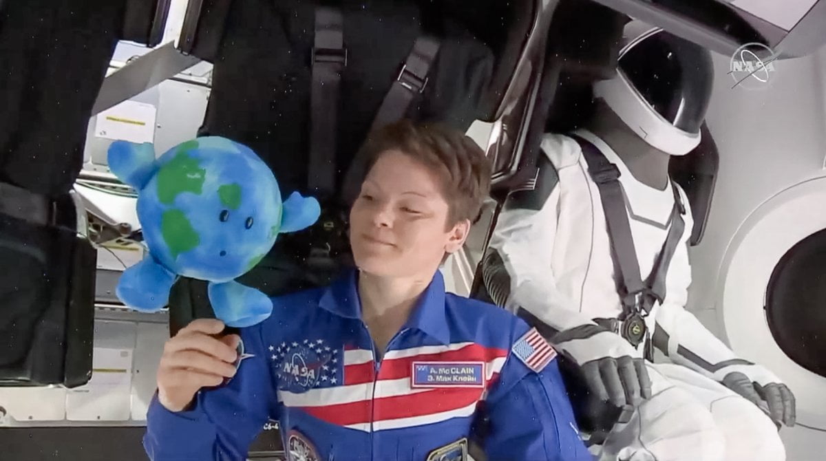 A Photo Of Woman In Space With Spacex'S Special Suite And A Toy Earth