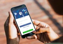 A photo of iPhone X in hands of a female with Facebook login screen open