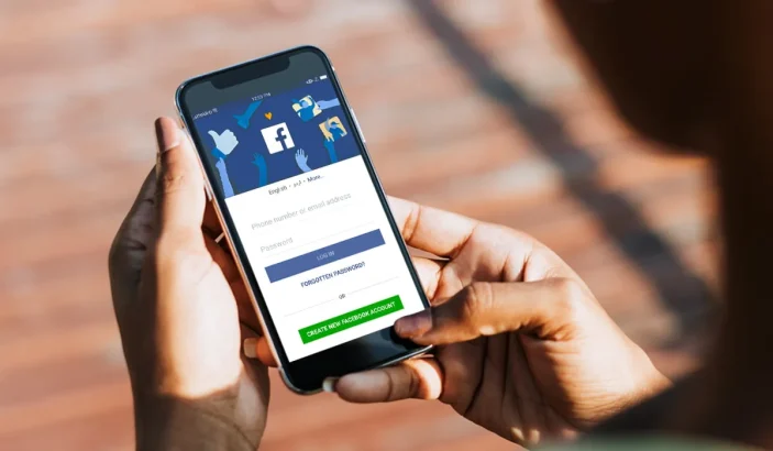 A photo of iPhone X in hands of a female with Facebook login screen open