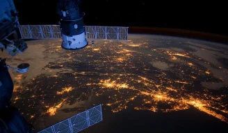 An image of space craft in the space with a stunning view of night lights on earth
