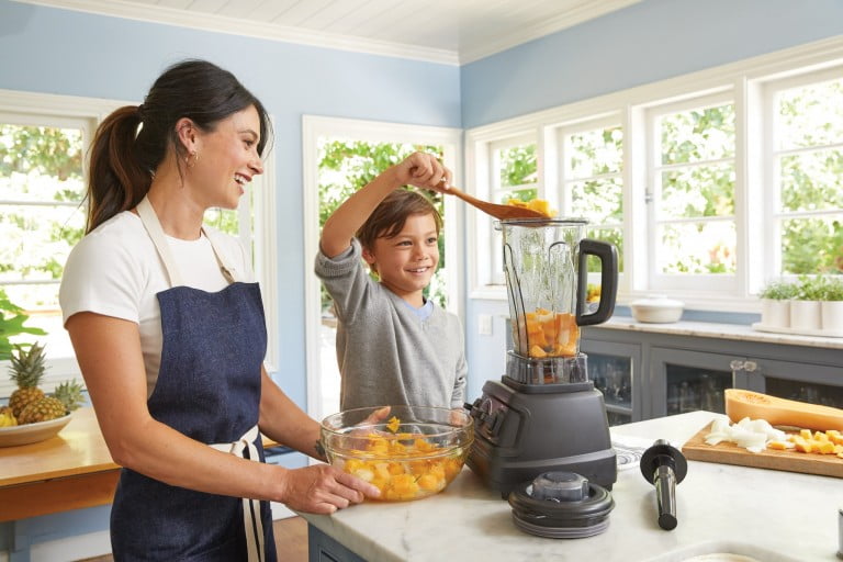 a child helping his mother in making food using food choppers