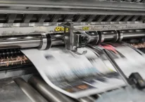 A photo of Newspaper machine printing out Newspapers