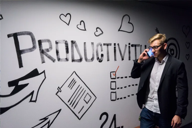 A photo of a man passing by sign of "Productivity" while talking on phone
