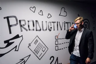A photo of a man passing by sign of "Productivity" while talking on phone