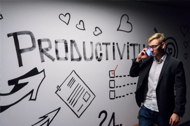 A photo of a man passing by sign of "Productivity" while talking on phone