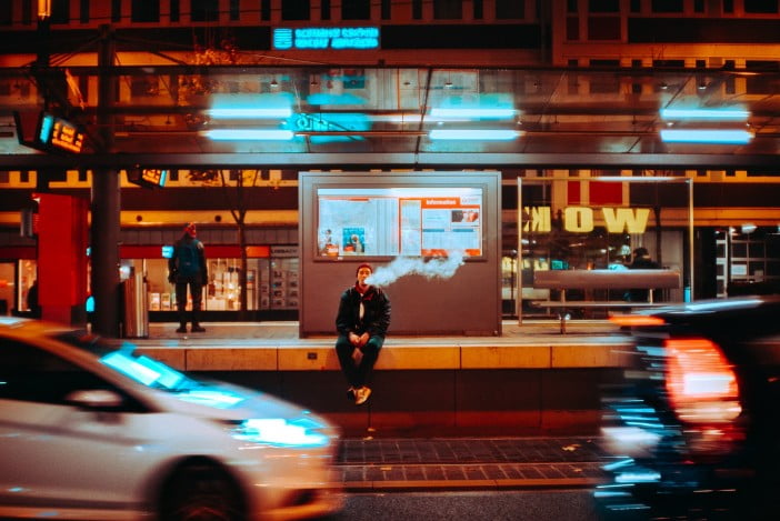 A Person Vaping On A Sidewalk In The City