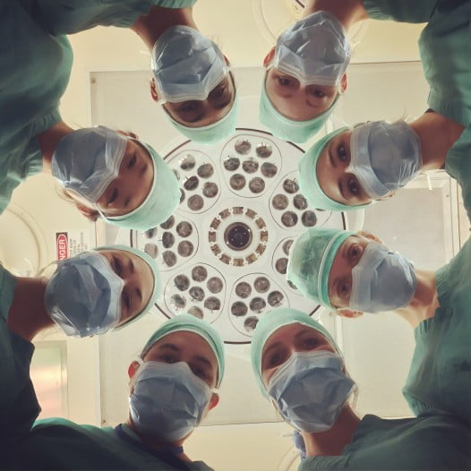 A Group Of Doctors While Operating A Patient