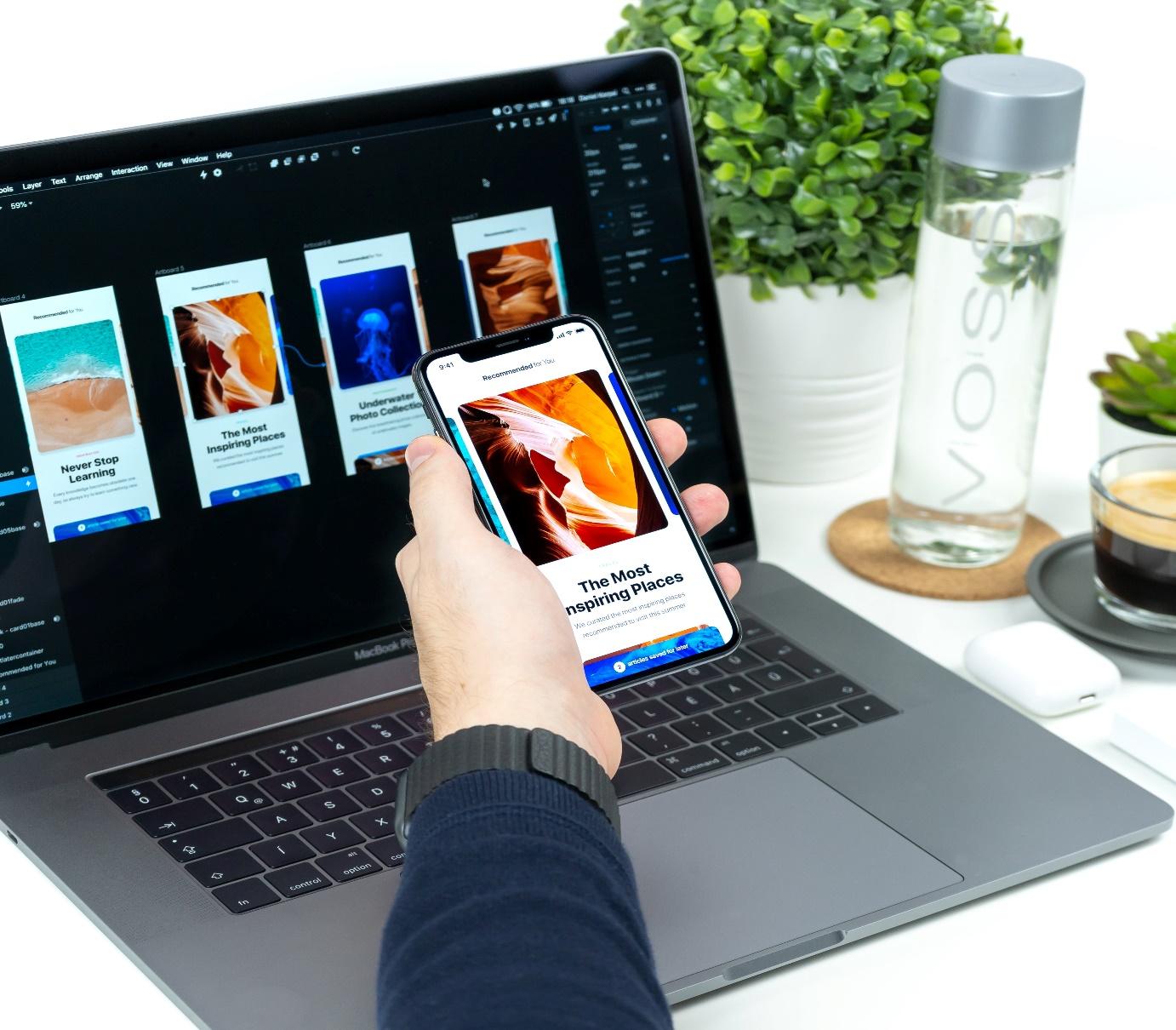 A person using a smartphone with a laptop
