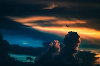 An Airplane passes through clouds during sunset