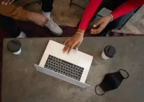 unrecognizable black colleagues browsing laptop at table with face mask