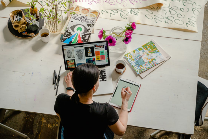 An Artist Using Her Ipad And Macbook At The Same Time For Creating Art