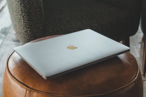 a laptop lying on a leather puff