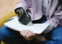 woman with modern prosthesis of hand writing in notebook